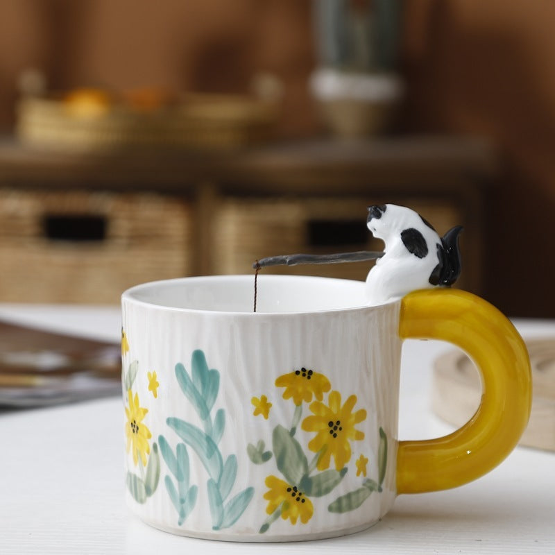 Cozy tea mug with green handle and painted design